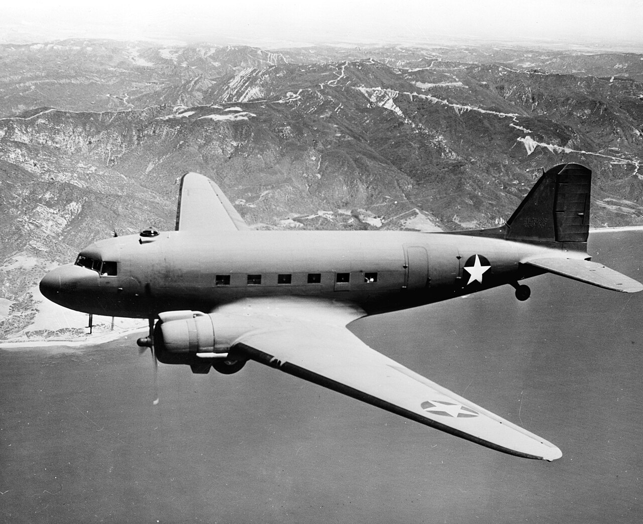 Bimoteur Douglas C-47 en vol au-dessus des nuages, photographie noir et blanc.