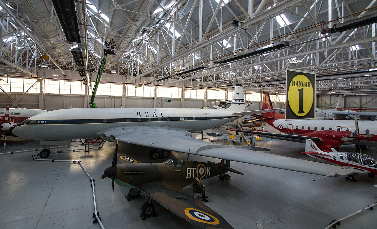 Avion de ligne de Havilland Comet blanc et bleu aux couleurs BOAC, exposé dans un hangar de musée.